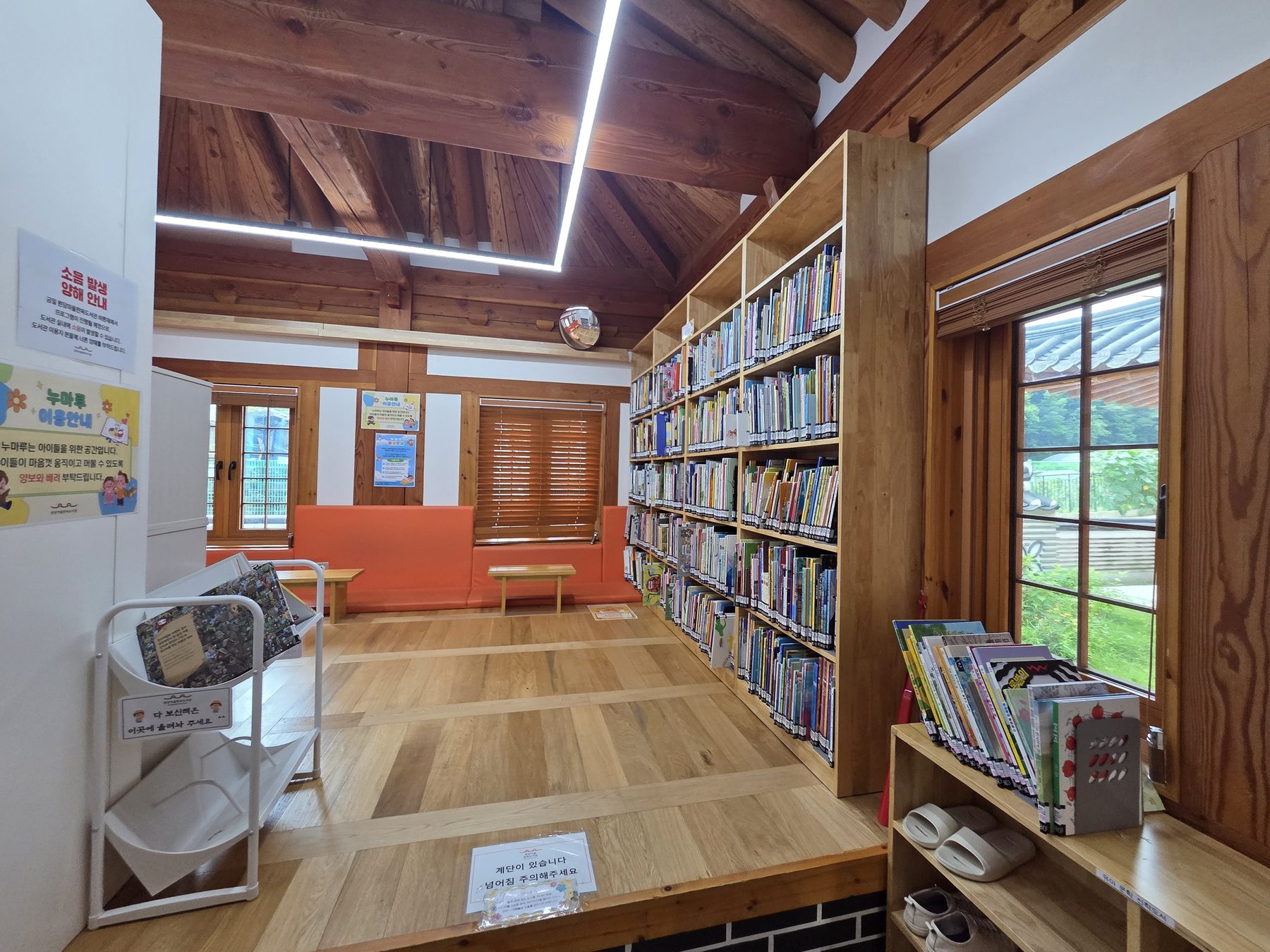 The children's room, a raised wooden floor with an orange cushioned bench and full bookshelves