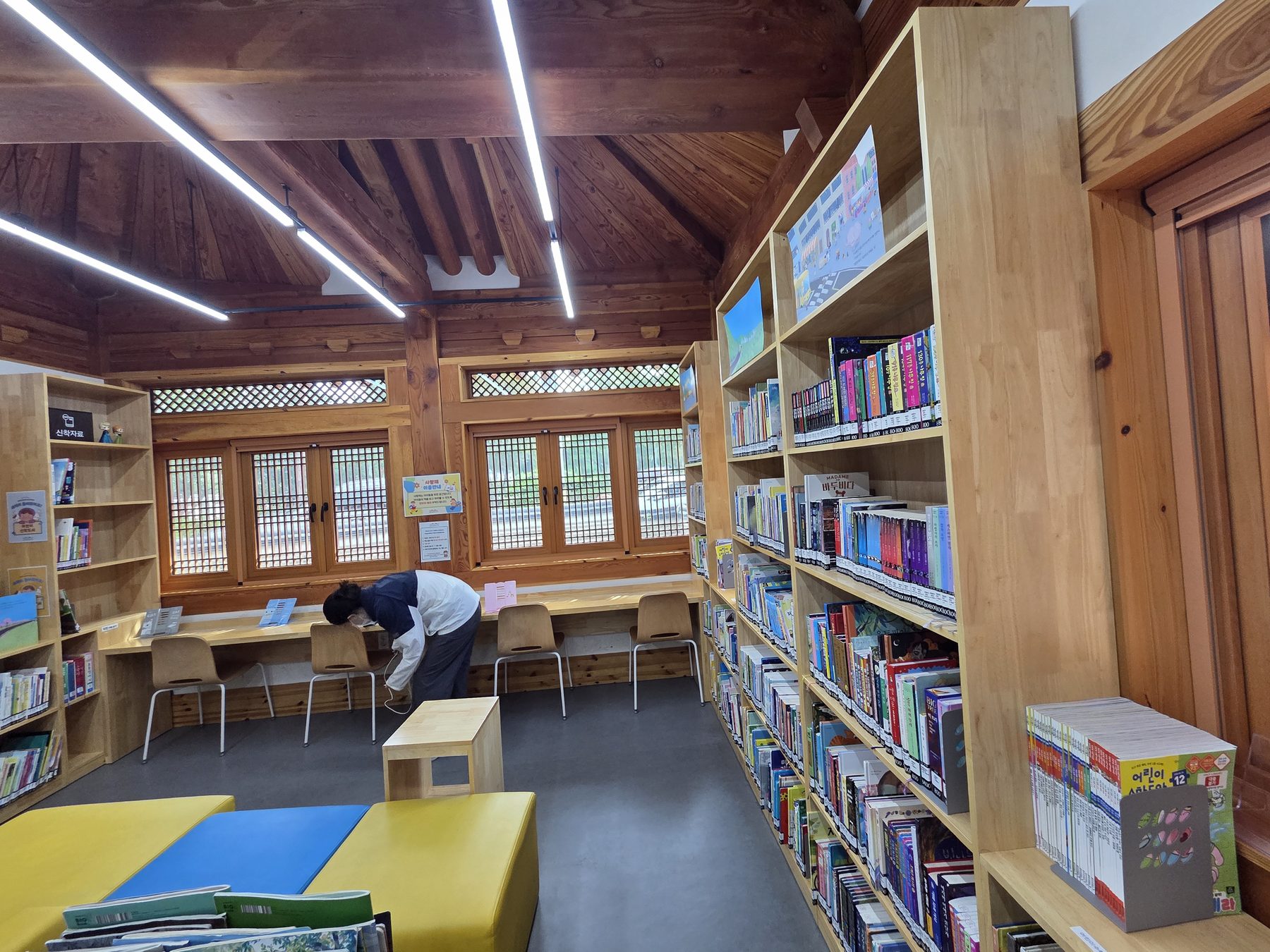 A reading room under exposed timber rafters, with lattice windows and a long desk