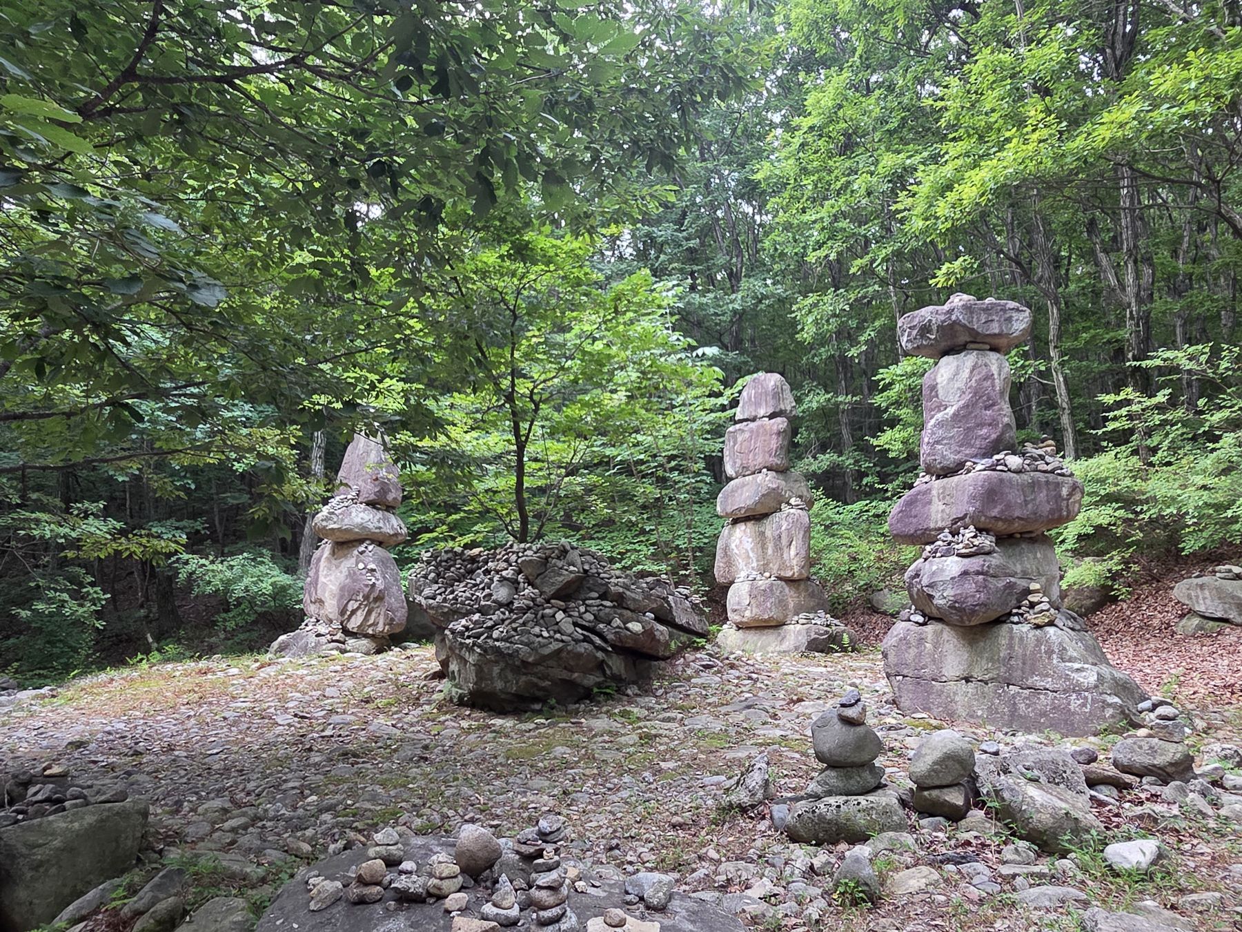 Tall stone cairns in a forest clearing along the trail