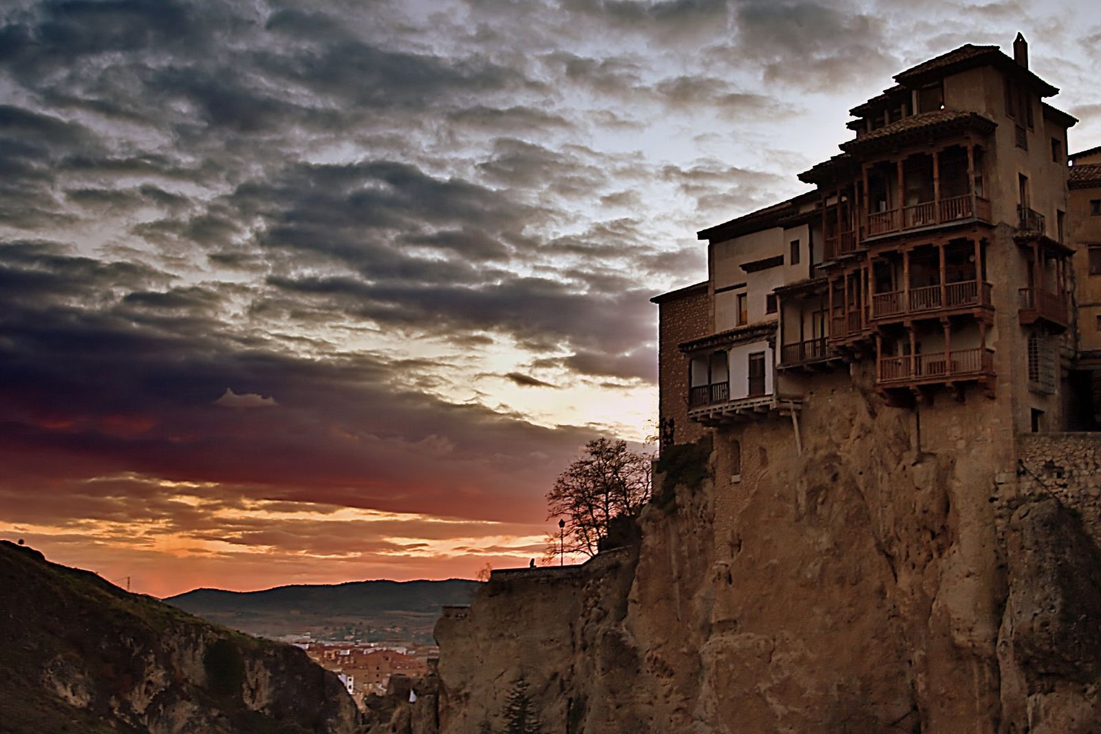 The Casas Colgadas of Cuenca, Spain: tall houses with wooden balconies perched on the edge of a rocky cliff at sunset