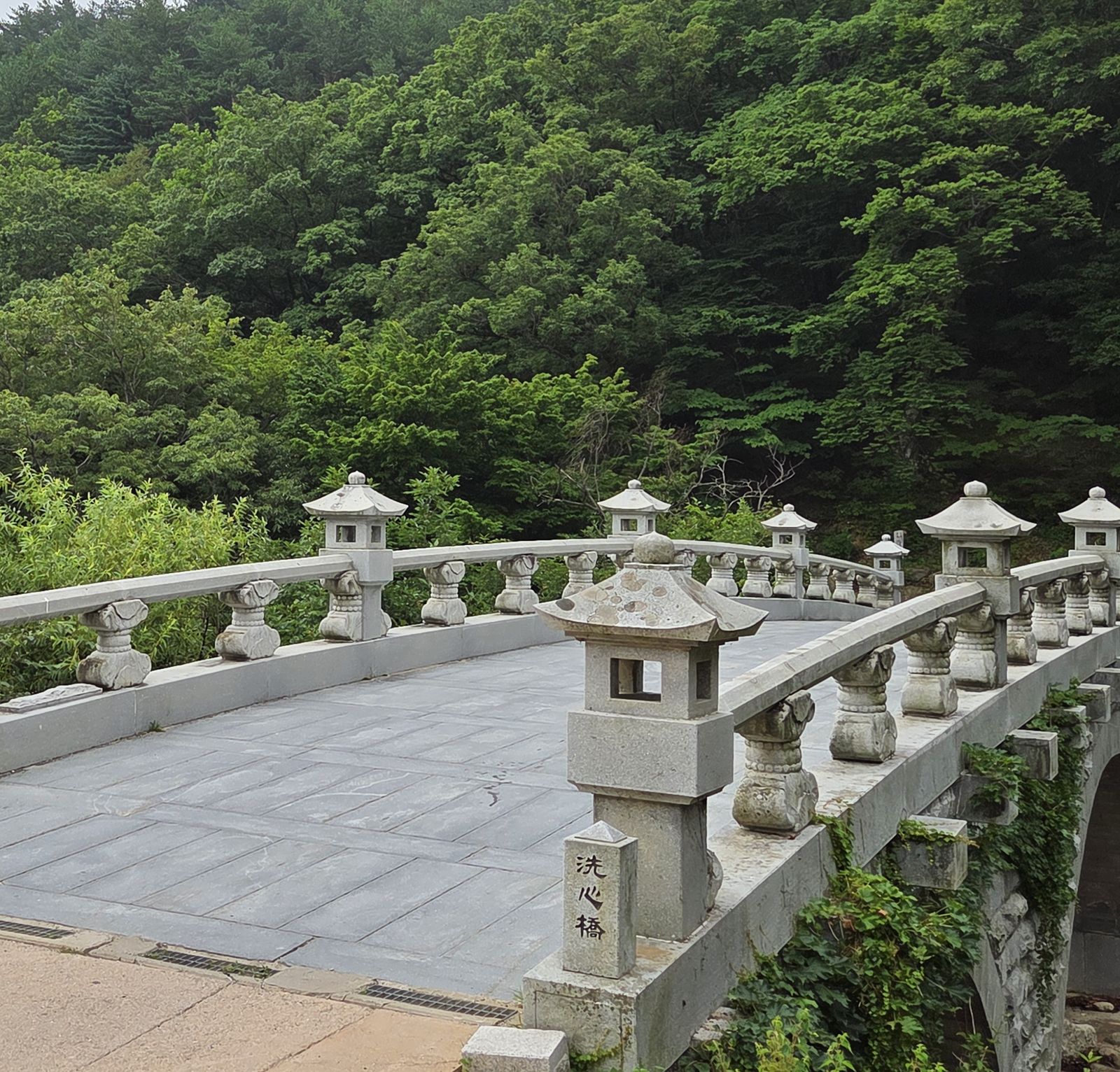 Sesimgyo, a stone bridge lined with lantern posts, with the carved marker 洗心橋 at its end