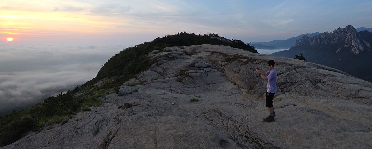 Sunrise over a sea of clouds seen from the granite top of Sinseondae, with the jagged ridge of Ulsanbawi on the right